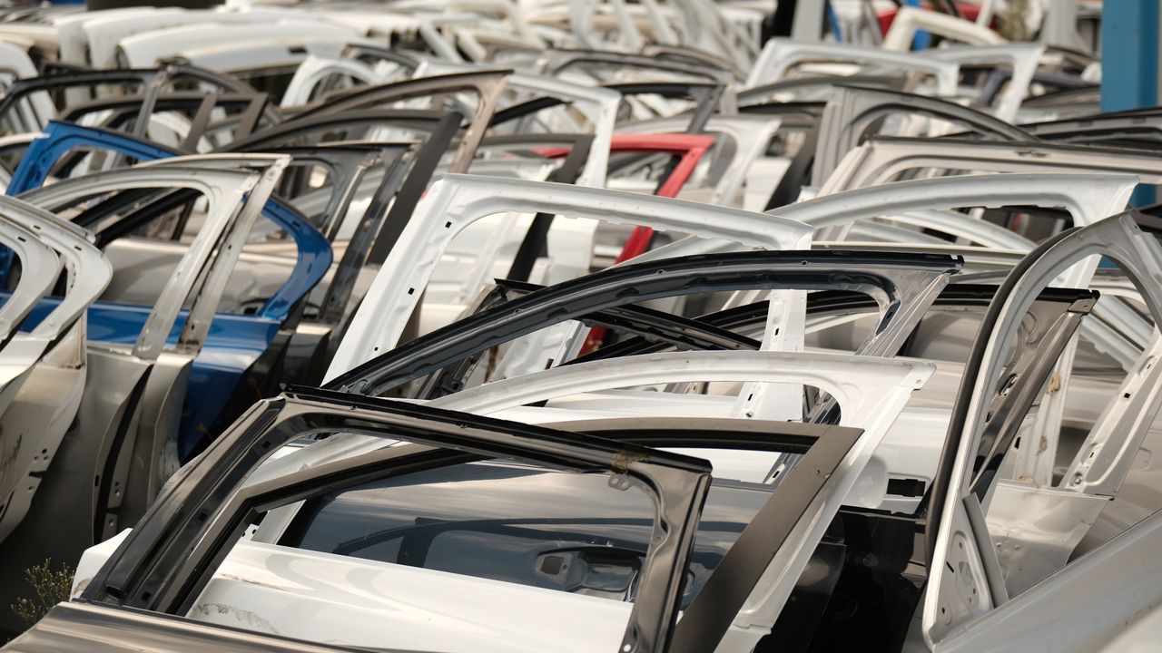 A variety of car doors in different colors arranged in a junkyard setting.