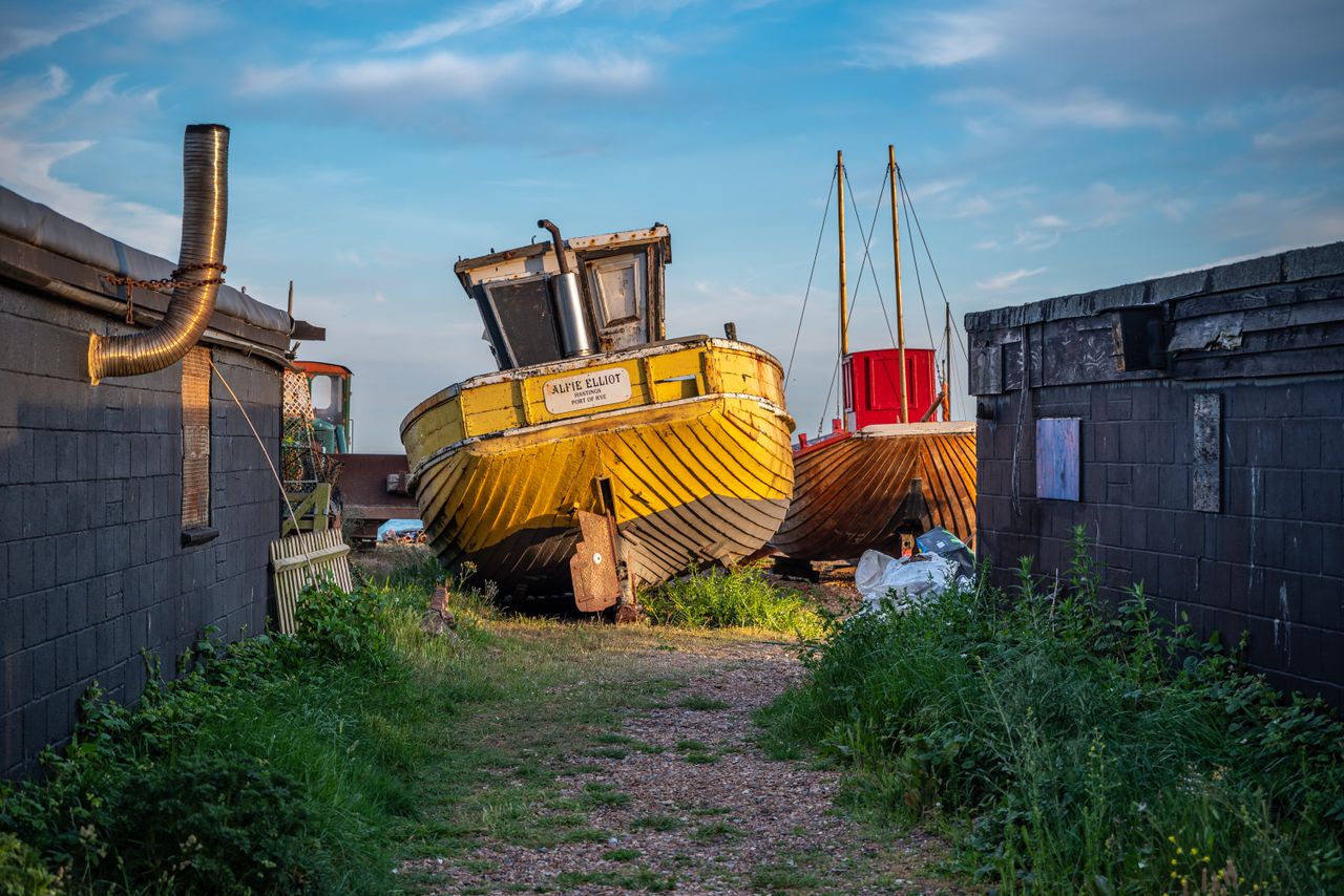 Colorful boats in a scrapyard setting in Hastings, capturing an abandoned and vintage feel.