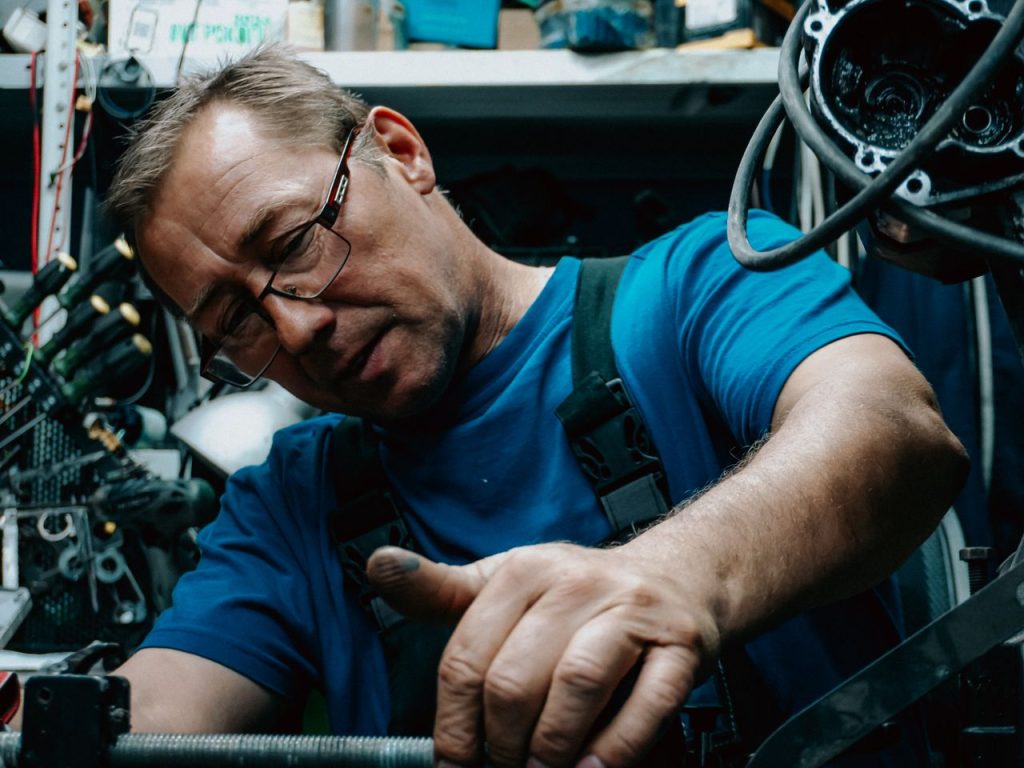 Close-up of a mechanic working on an engine, showcasing expertise and focus in an auto repair shop.